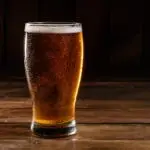 Glass of light beer on a dark pub